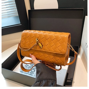 Detail of hand-woven orange leather bag with golden lock and strap in gift box