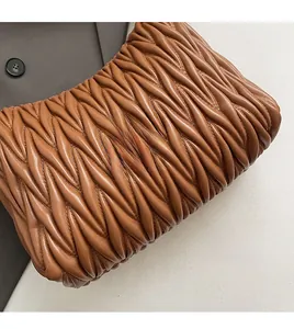 Detailed view of brown ruched leather bucket bag with textured woven pattern