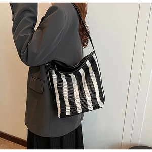 Breathable mesh striped shoulder bag with leather base worn by a model in a suit
