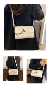 Detail of white woven leather crossbody bag with a distinctive gold metal knot lock