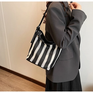 Close-up of woven mesh texture and black leather strap on a striped shoulder bag