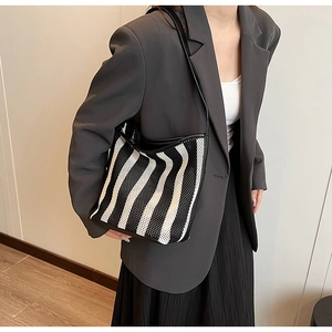 Detail of black and white striped tote bag with mesh texture and black shoulder strap