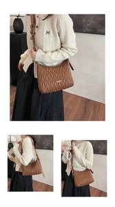 Close-up of brown pleated PU leather bag featuring a cute bow and metallic logo plate