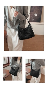 Detailed view of black matelassé quilted shoulder bag with adjustable leather strap