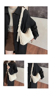 Detail of white pleated shoulder bag with vertical textures and adjustable wide strap