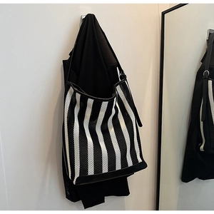Detail view of black and white striped tote bag featuring breathable mesh texture and leather trim