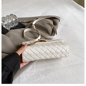 Detail of white woven leather handbag with gold clasp and fine shoulder strap
