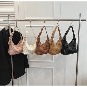 Detail view of five pleated hobo bags in various colors hanging on a metal display rack