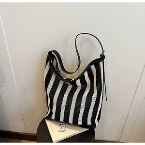 Detail of striped mesh tote bag featuring woven texture and black leather shoulder strap