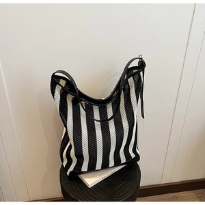 Detail of black and white striped tote bag showing mesh texture and leather straps