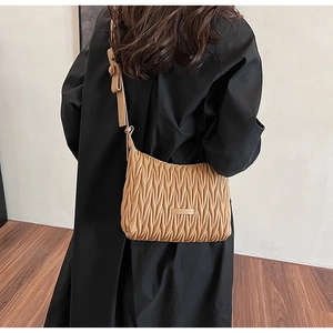 Close-up of pleated texture and bow detail on khaki quilted crossbody bag