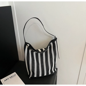 Detail of black and white striped mesh tote bag with smooth leather trim and thin straps