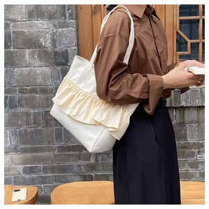 Detail of white canvas tote bag featuring yellow pleated ruffle trim and minimalist design