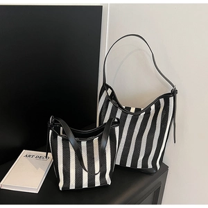 Detail view of large and small black and white striped tote bags with leather straps