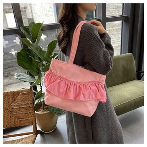 Detail shot of a pink canvas tote bag with ruffles worn over the shoulder by a model