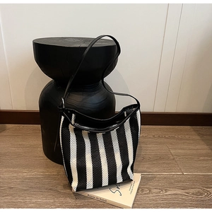 Detail view of the breathable mesh texture and black leather strap on striped shoulder bag