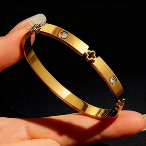Polished gold stainless steel bangle with diamond zircon and hollow floral design