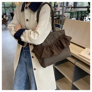 Detail of coffee brown canvas tote bag featuring decorative ruffle pleats and texture