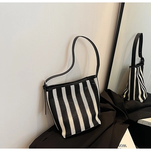 Detail of striped mesh shoulder bag with black leather straps and adjustable buckle