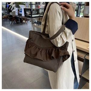 Close-up of brown canvas tote bag featuring layered ruffle pleats and wide shoulder straps