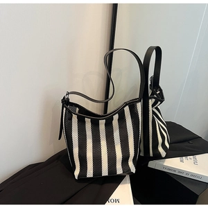 Detail view of black and white striped bucket bag with leather strap and reinforced base