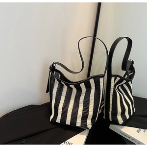 Close-up of black and white striped mesh tote bag with premium leather trim and silver hardware