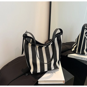 Detail of black and white striped knit mesh tote bag with smooth black leather handles
