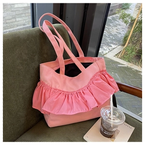 Detailed view of pink canvas tote bag with decorative ruffle pleats on a textured seat