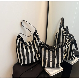 Detail of black and white striped mesh tote bags in two sizes with sleek leather handles