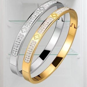 Detail of clover and diamond-set stainless steel bangles in gold and silver finish