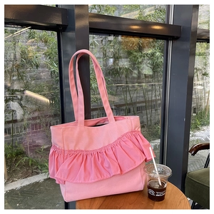 Detail of pink canvas tote bag with ruffle trim decoration on a rustic wooden table