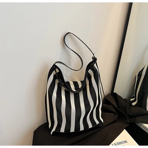Detail of striped mesh tote bag featuring premium leather straps and woven texture