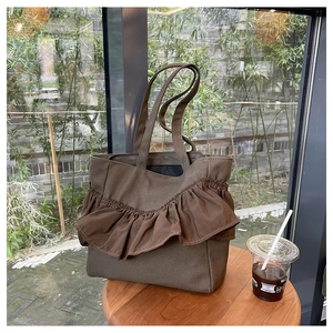 Detail of a brown canvas tote bag featuring stylish ruffle pleats and dual handles