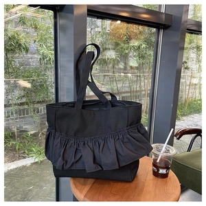 Detail of ruffled black canvas tote bag on a wooden table near a sunlit window
