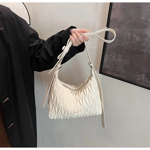Detail of white quilted ruched shoulder bag with matelassé texture and adjustable strap