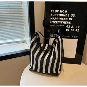 Detail view of a black and white striped knit tote bag with premium leather straps