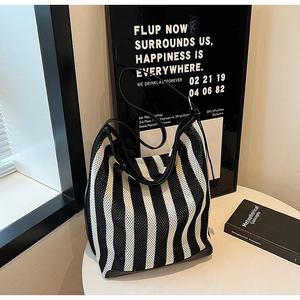 Detail of striped knit tote bag with mesh texture and black leather shoulder strap