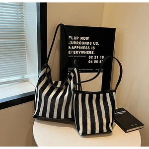 Detail view of large and small striped knit tote bags with black leather straps and base