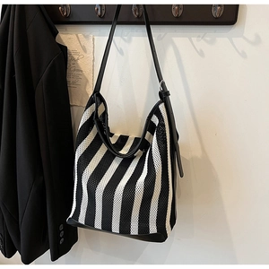 Detail of a black and white striped knit tote bag featuring an adjustable leather strap