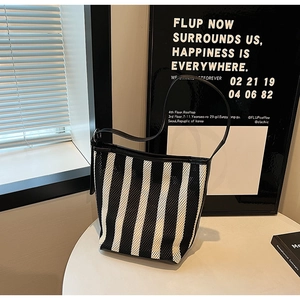 Detail of black and white striped mesh tote bag with black leather shoulder strap