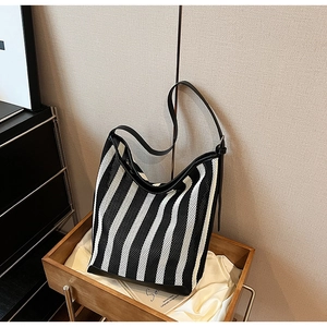 Detail of striped tote bag showing breathable hollow mesh fabric and black leather trim