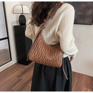Detail of dark brown pleated matelassé hobo shoulder bag with bow knot on strap