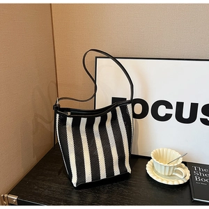 Detail of black and white striped knit mesh tote bag with smooth black shoulder strap