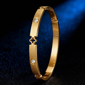 Detail eines goldenen Kleeblatt-Armreifs mit mattem Finish und funkelnden Zirkonia-Steinen