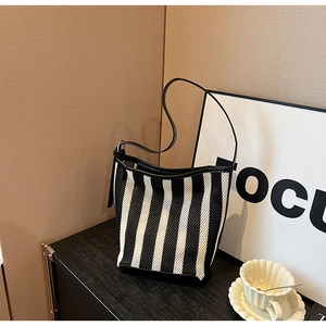 Detail of black and white striped bucket bag featuring mesh texture and leather strap