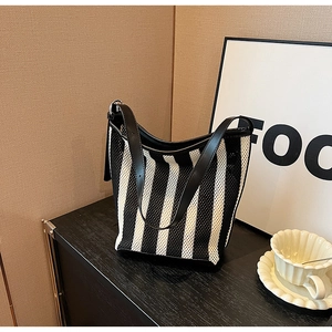 Detail of black and white striped mesh tote bag with smooth black leather strap