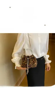 Detailed view of leopard print bucket bag with silver chain strap and metal fringe