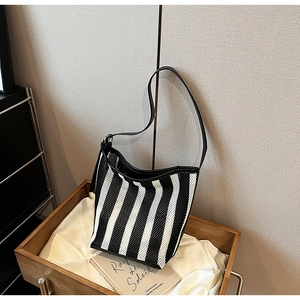 Detail of black and white striped shoulder bag featuring mesh texture and leather straps