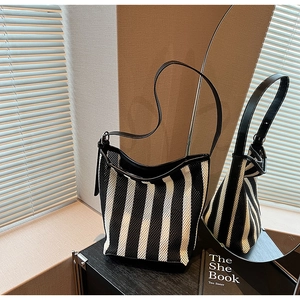 Detail of striped mesh bucket bag with leather trim under artistic sunlight shadows