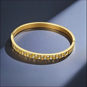 Detail of gold double-row rhinestone bangle with checkered texture on blue leather